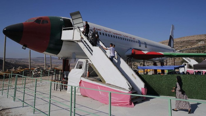 Palestinians visit the cockpit of a Boeing 707 after the plane was converted to a cafe restaurant, in Wadi Al-Badhan, near the West Bank city of Nablus, Wednesday, Aug. 11, 2021. The Palestinian territory has no civilian airport and those who can afford a plane ticket must catch their flights in neighboring Jordan. After a quarter century of effort, twins brothers, Khamis al-Sairafi and Ata, opened the “Palestinian-Jordanian Airline Restaurant and Coffee Shop al-Sairafi” on July 21, 2021, offering people an old airplane for customers to board. (AP Photo/Majdi Mohammed)
