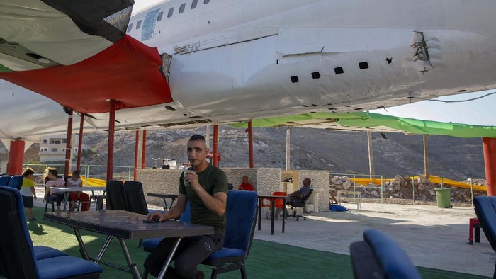 Palestinians visit the cockpit of a Boeing 707 after the plane was converted to a cafe restaurant, in Wadi Al-Badhan, near the West Bank city of Nablus, Wednesday, Aug. 11, 2021. The Palestinian territory has no civilian airport and those who can afford a plane ticket must catch their flights in neighboring Jordan. After a quarter century of effort, twins brothers, Khamis al-Sairafi and Ata, opened the “Palestinian-Jordanian Airline Restaurant and Coffee Shop al-Sairafi” on July 21, 2021, offering people an old airplane for customers to board. (AP Photo/Majdi Mohammed)