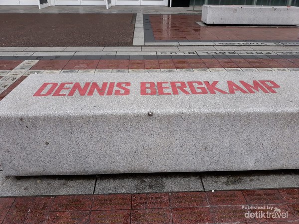 Bangku semen bertulis nama Dennis Bergkamp di halaman stadion