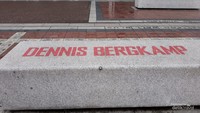 Bangku semen bertulis nama Dennis Bergkamp di halaman stadion