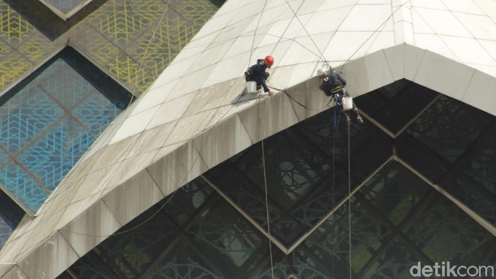Pemeliharaan dan kebersihan Masjid Al Jabbar terus dilakukan. Salah satunya bagian eksterior yang dilakukan pekerja dengan cara gelantungan.