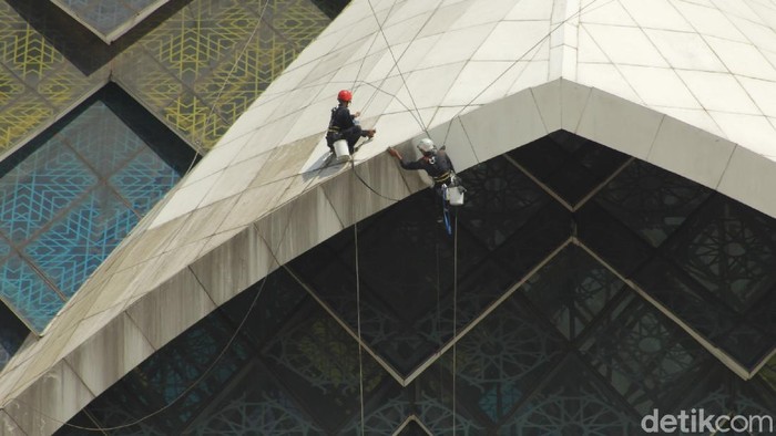 Pemeliharaan dan kebersihan Masjid Al Jabbar terus dilakukan. Salah satunya bagian eksterior yang dilakukan pekerja dengan cara gelantungan.
