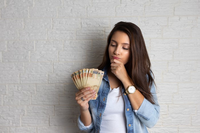 Young pretty woman is looking at cash banknotes, Brazil Currency. Financial, profit, credit, cost, purchase, rich concept.