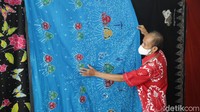 Seorang warga memamerkan batik yang sudah siap dijual.