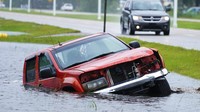 Sebuah mobil terhempas hingga masuk ke selokan di Bay Saint Louis. AP Photo/Eric Gay.