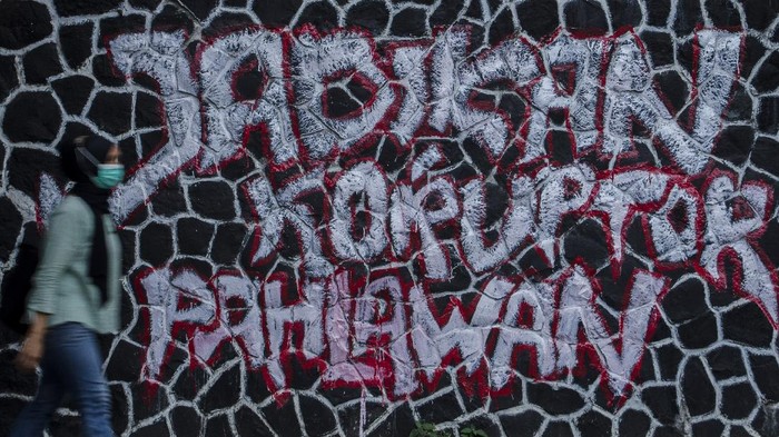 MURAL KRITIK KPK Warga melintas di depan mural kritik bertuliskan