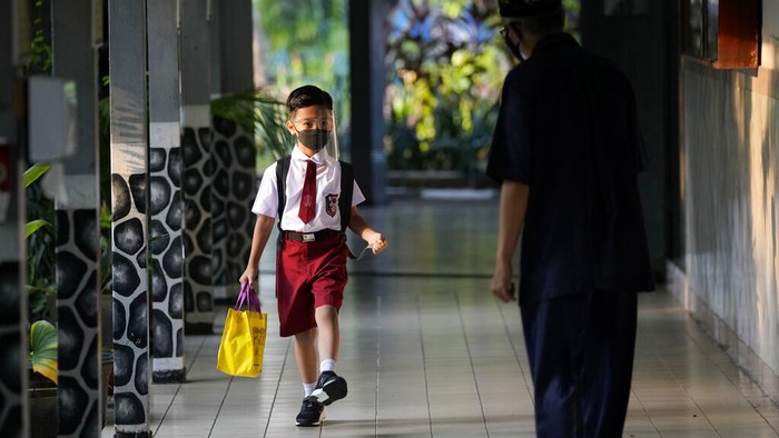 Students wearing face masks to prevent the spread of COVID-19 wash their hands before entering a school building on the first day its reopening in Jakarta, Indonesia, Monday, Aug. 30, 2021. Authorities in Indonesia's capital kicked off the school reopening after over a year of remote learning on Monday as the daily count of new COVID-19 cases continues to decline. (AP Photo/Dita Alangkara)
