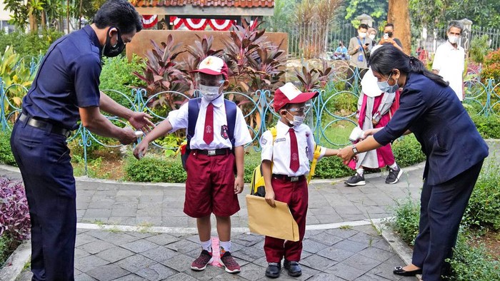 Students wearing face masks to prevent the spread of COVID-19 wash their hands before entering a school building on the first day its reopening in Jakarta, Indonesia, Monday, Aug. 30, 2021. Authorities in Indonesia's capital kicked off the school reopening after over a year of remote learning on Monday as the daily count of new COVID-19 cases continues to decline. (AP Photo/Dita Alangkara)