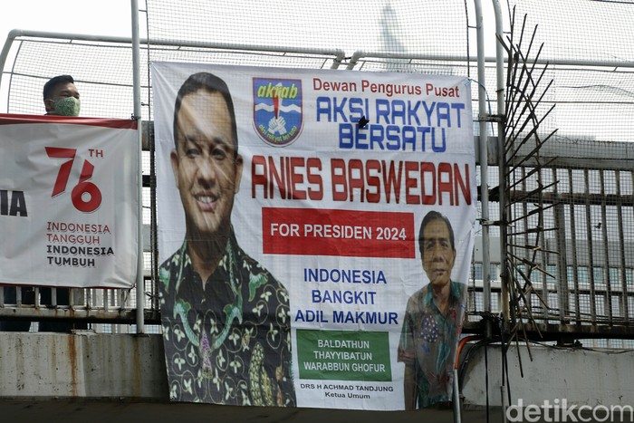 Warga melintas di JPO yang terpasang spanduk Anies Baswedan 