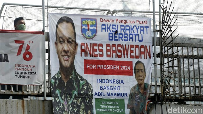 Warga melintas di JPO yang terpasang spanduk Anies Baswedan 