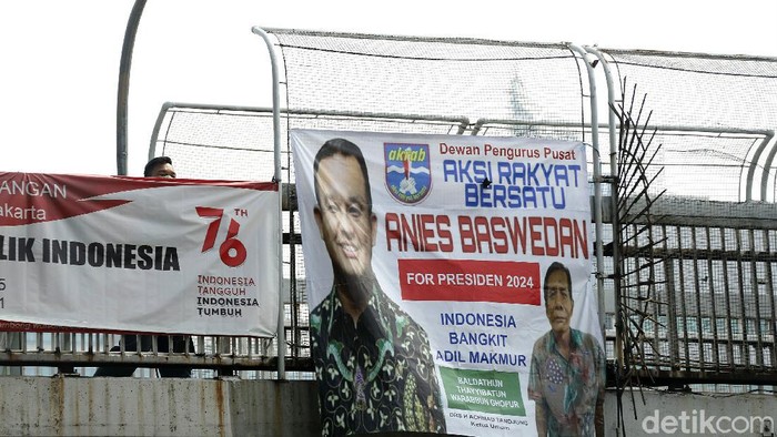 Warga melintas di JPO yang terpasang spanduk Anies Baswedan 