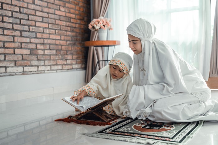 mother and kid reading quran together at home