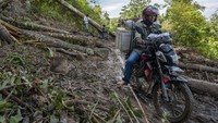 Seorang pengendara sepeda motor melitas di ruas Jalan Trans Palu-Kulawi yang tertimbun material longsoran di Desa Salua, Sigi, Sulawesi Tengah, Selasa (31/8/2021).