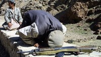 Anggota Aliansi Utara melakukan sholat di tengah medan pertempuran di Salang, 35 mil utara Kabul (5/10/2001).  (Photo by Oleg Nikishin/Getty Images)