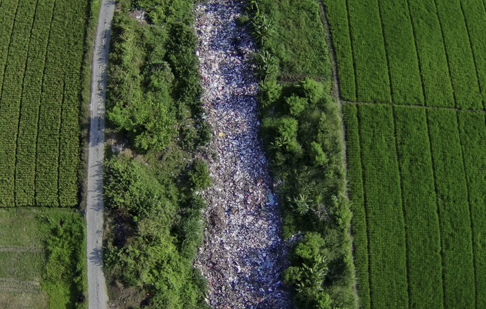 Foto udara aliran Kali Busa dipenuhi sampah plastik di Tambun Utara, Kabupaten Bekasi, Jawa Barat, Rabu (1/9/2021). Menurut warga tumpukan sampah sepanjang 200 meter yang berasal dari limbah rumah tangga sudah berada di aliran kali tersebut selama enam bulan. ANTARA FOTO/Fakhri Herrmansyah/rwa.