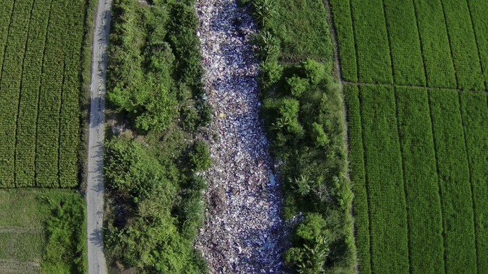 Foto udara aliran Kali Busa dipenuhi sampah plastik di Tambun Utara, Kabupaten Bekasi, Jawa Barat, Rabu (1/9/2021). Menurut warga tumpukan sampah sepanjang 200 meter yang berasal dari limbah rumah tangga sudah berada di aliran kali tersebut selama enam bulan. ANTARA FOTO/Fakhri Herrmansyah/rwa.