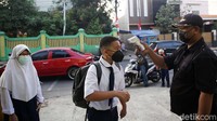 Para siswa akan dicek suhu tubuhnya sebelum memasuki kelas. Mereka juga wajib cuci tangan dengan sabun.