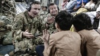 Tentara Joint Task Force-Crisis Response (JTF-CR) menghibur anak-anak di dalam Boeing C-17 Globemaster III selama proses evakuasi terakhir di Bandara Internasional Hamid Karzai di Kabul, Afghanistan.  