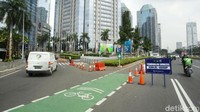 Barrier berwarna oranye terpasang melintang di tengah jalan. Selain itu ada pula papan peringatan bertulisan Pengendalian Mobilitas Ganjil-Genap di lokasi.