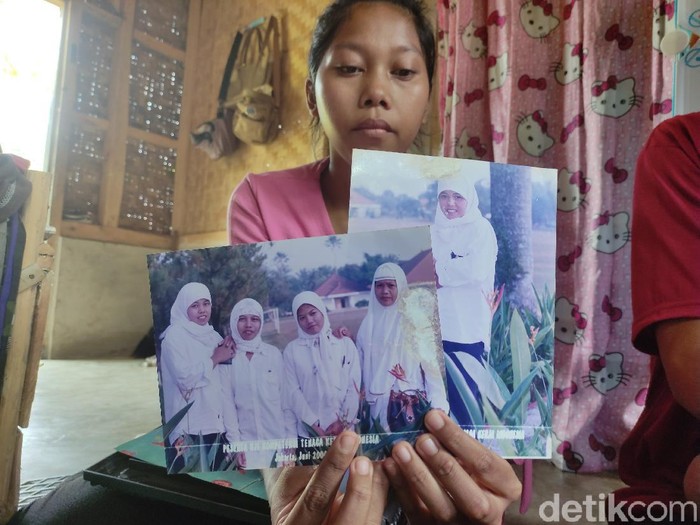 Repi, anak dari TKI Yeti memegang foto terakhir ibunya sebelum hilang kontak selama 17 tahun.