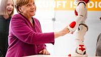Ekpresi Merkel saat bertemu robot buatan Frauenhofer Institut di Berlin (25/4/2018). Tugas terbesar pertama yang dihadapi Merkel saat baru menjabat sebagai kanselir adalah ambruknya pasar uang akibat krisis keuangan tahun 2008. Kebijakannya yang keras mampu menyelamatkan perekonomian Eropa dengan membentuk dana moneter penyelamat mata uang Euro. (Carsten Koall/Getty Images)