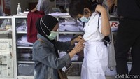 Tampak seorang ibu tengah mencocokan ukuran seragam untuk anaknya.