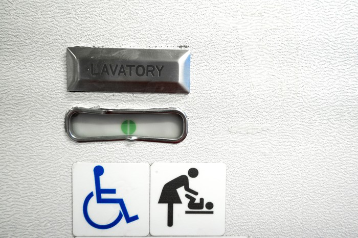 A sign in the toilet of an airplane, meaning that the toilet is equipped for disabled people. And it has a changing table.