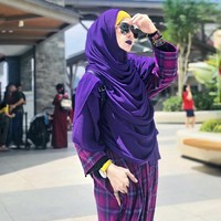 Sarah Vi membagikan foto OOTD di akun Instagramnya @sarahvi_ dengan berbagai model outfit. Tampil berbeda, Sarah memilih riasan makeup yang unik, seperti memakai warna lipstik yang senada dengan outfitnya. Dalam foto ini Sarah Vi mengaplikasikan lipstik warna ungu matte yang senada dengan khimarnya. Ia juga mengenakan tartan gamis saat berada di luar rumah. Foto: Dok. Instagram @sarahvi_.