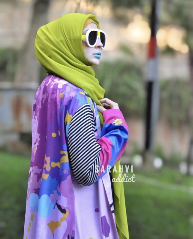 Semenjak hijrah, Sarah Vi membuat desaina busana muslim yang antimainstream. Pilihan busananya tabrak warna dan motif yang tak biasa. Seperti salah satu koleksinya ini yang menggunakan motif garis-garis pada lengan dan motif abstrak. Dia pun bergaya dengan memakai lipstik yang matching dengan keunikan busananya. Foto: Dok. Instagram @sarahvi_.