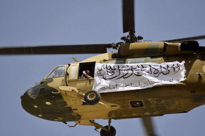 A helicopter displaying a Taliban flag flies above Taliban supporters gathered to celebrate the US withdrawal of all its troops out of Afghanistan, in Kandahar on September 1, 2021 following the Talibans military takeover of the country. (Photo by JAVED TANVEER / AFP)