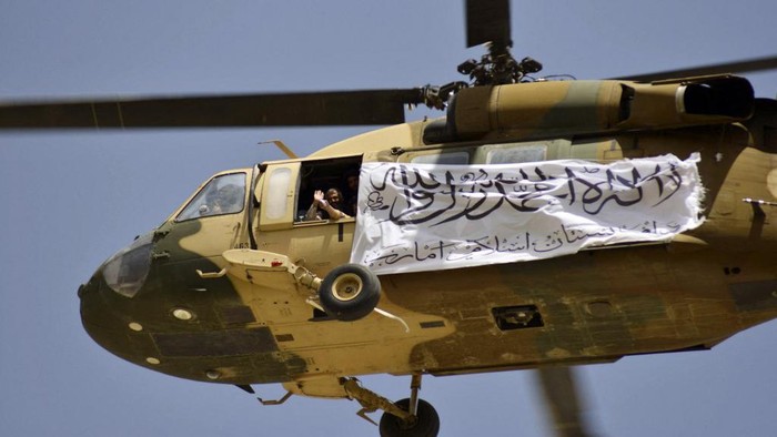 A helicopter displaying a Taliban flag flies above Taliban supporters gathered to celebrate the US withdrawal of all its troops out of Afghanistan, in Kandahar on September 1, 2021 following the Talibans military takeover of the country. (Photo by JAVED TANVEER / AFP)