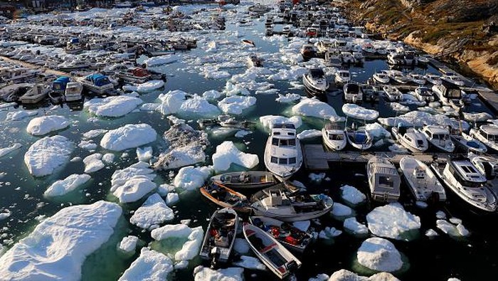 Es di Greenland Terus Cair, Sinyal Memburuknya Pemanasan Global ILULISSAT, GREENLAND - SEPTEMBER 02: A pedestrian walks as ice and icebergs float in Disko Bay on September 02, 2021 in Ilulissat, Greenland. Greenland in 2021 is experiencing one of its biggest ice-melt years in recorded history. Scientists studying the Greenland Ice Sheet observed rainfall on the highest point in Greenland for the first time ever this August. Researchers from Denmark estimated that in July of this year enough ice melted on the Greenland Ice Sheet to cover the entire state of Florida with two inches of water. The observations come on the heels of the recent United Nations report on global warming which stated that accelerating climate change is driving an increase in extreme weather events. (Photo by Mario Tama/Getty Images)