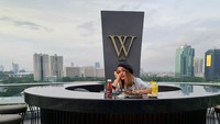 Seperti yang terlihat di foto yang satu ini. Memperlihatkan Indah Sari tengah menikmati orange juice di kafe di atas ketinggian. Foto: Instagram @indahsariofficial