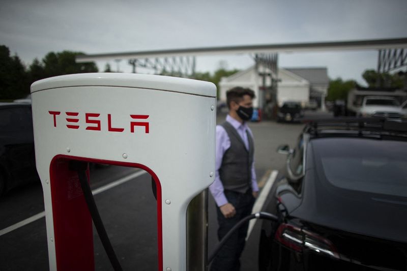 Ben Rich charges his Tesla vehicle at a super charging station in Parsippany, New Jersey on May 06, 2021. - With more electrical models soon hitting showrooms, the focus will shift to consumer willingness to pivot to electric cars at a time when conventional gas stations remain familiar and ubiquitous. (Photo by Kena Betancur / AFP)