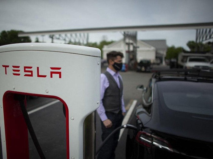 Ben Rich charges his Tesla vehicle at a super charging station in Parsippany, New Jersey on May 06, 2021. - With more electrical models soon hitting showrooms, the focus will shift to consumer willingness to pivot to electric cars at a time when conventional gas stations remain familiar and ubiquitous. (Photo by Kena Betancur / AFP)