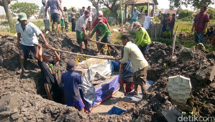 Warga memindahkan 5 peti jenazah dari makam sementara ke Tempat Pemakaman Umum (TPU) permanen di Dusun Kudu, Desa Weduni, Kecamatan Glagah, Lamongan, Jawa Timur, Sabtu (4/9).