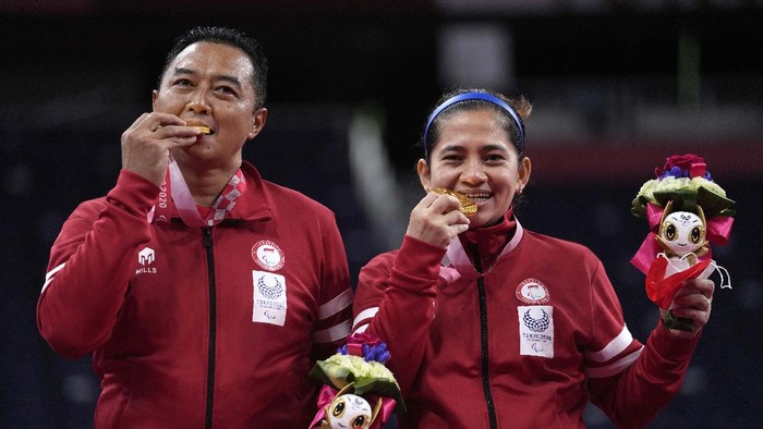 Indonesia's Hary Susanto, left, and Leani Ratri Oktila salute to the flag during the national anthem after receiving a gold medal for mixed doubles SL3-SU5 gold medal match at the Tokyo 2020 Paralympic Games, Sunday, Sept. 5, 2021, in Tokyo, Japan. (AP Photo/Kiichiro Sato)