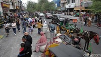 Wisatawan ada yang berbelanja oleh-oleh, ada pula yang duduk-duduk sembari makan menikmati minggu sore di kawasan Jalan Malioboro.