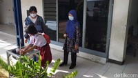 Para siswa dan orangtua yang datang ke sekolah wajib menggunakan masker dan mencuci tangan.