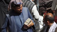 Warga membawa segepok uang kertas untuk ditukarkan di Pasar Sarai Shahzada, Kabul, Afghanistan. Pasar penukaran uang ini mulai menggeliat usai Taliban berkuasa pada pertengahan Agustus lalu.
