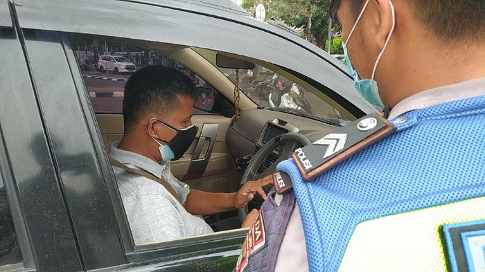 Polisi saat memberi tilang ke pemobil langgar ganjil genap di Jl Sudirman, Jakarta (Adhyasta-detikcom)