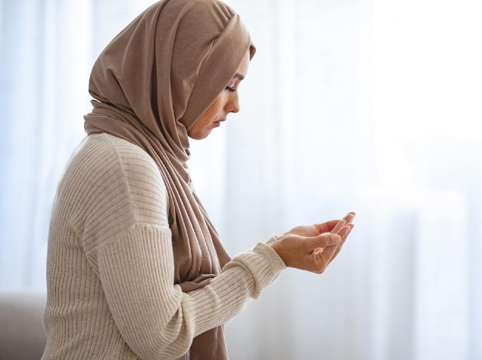 A female adult is putting both hands together for doa (Muslim way of praying) during partial lockdown in Malaysia.