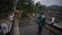 Seorang warga memotret kondisi jembatan yang ambruk diterjang banjir bandang.