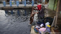 Seorang warga menyelesaikan mencuci pakaian di aliran sungai yang kotor dan menghitam tersebut.