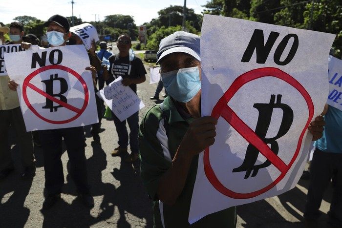 A man holds a sign with a message that reads in Spanish; 