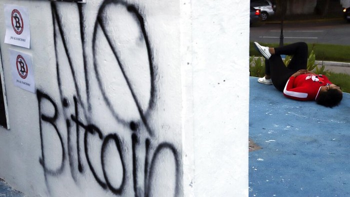 A man holds a sign with a message that reads in Spanish; 