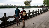 Dua orang warga melintas di kawasan patung Guan Yu yang sedang dibongkar.