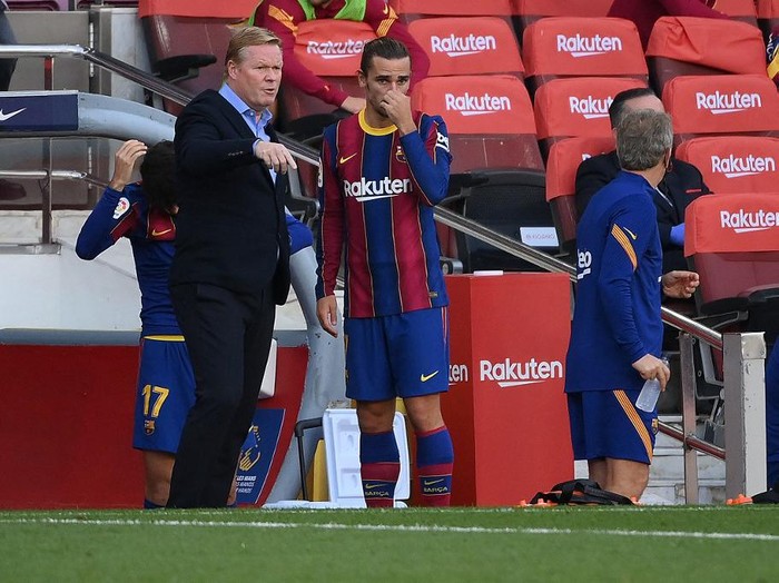 Barcelona's Dutch coach Ronald Koeman (L) speaks to Barcelona's French midfielder Antoine Griezmann before he enters the pitch during the Spanish League football match between Barcelona and Real Madrid at the Camp Nou stadium in Barcelona on October 24, 2020. (Photo by LLUIS GENE / AFP)