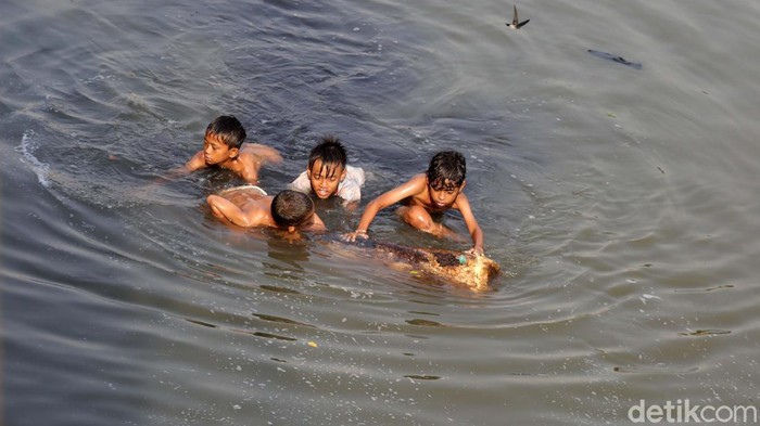 Sejumlah anak berenang di Banjir Kanal Timur (BKT), Cipinang, Jakarta. Mereka asyik berenang meski air sungai kotor dan berbusa.