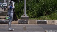 Nenek Mumun mengemis dengan menjadi manusia silver. Ia tampak memberi hormat kepada para pengendara.